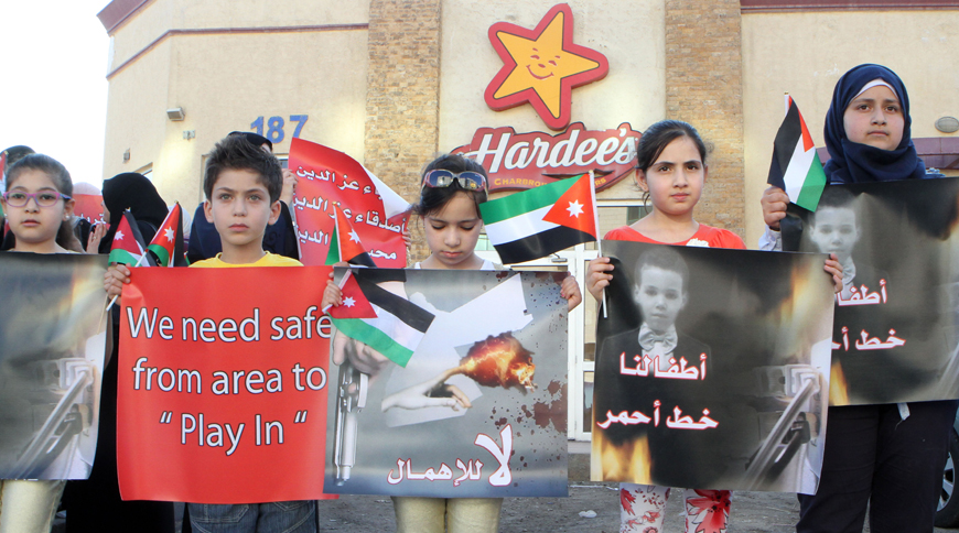 Children and activists participate in a protest near the Hardee’s branch on Medina Munawara Street in Amman on Thursday (Photo by Osama Aqarbeh)
